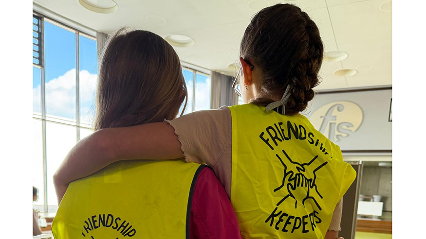 Two students wearing vests with the text friendship keepers
