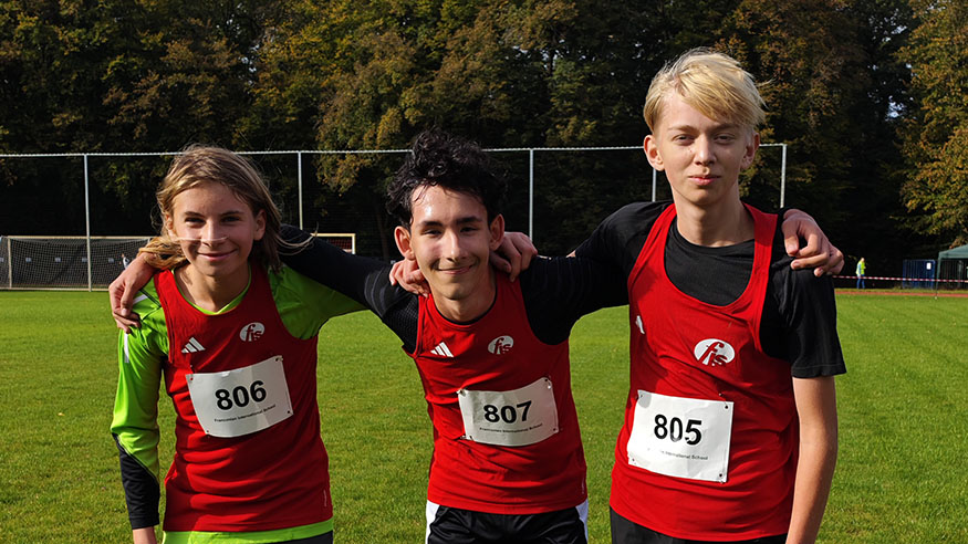 3 student athletes on a field after their cross country race